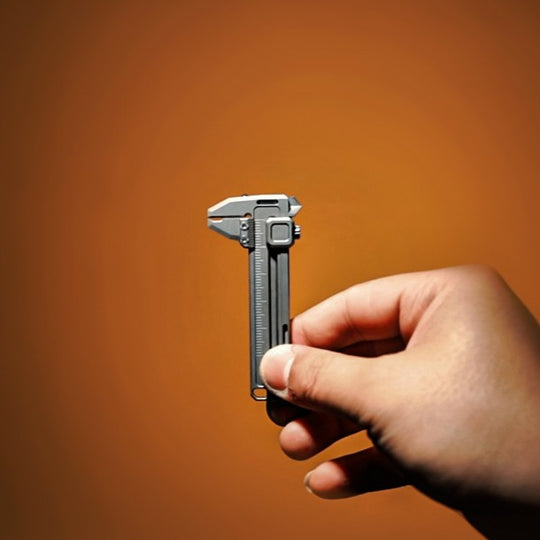 Hand holding a titanium mini caliper, compact precision measuring tool with minimalist design.